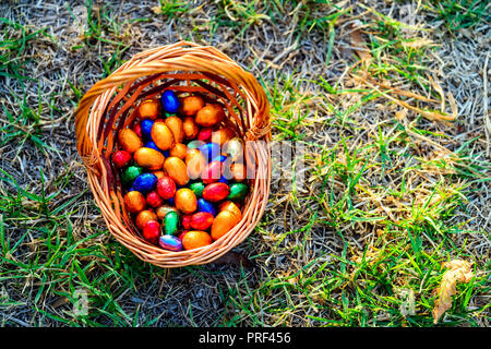 Colorful chocolate eggs in basket on grass Stock Photo