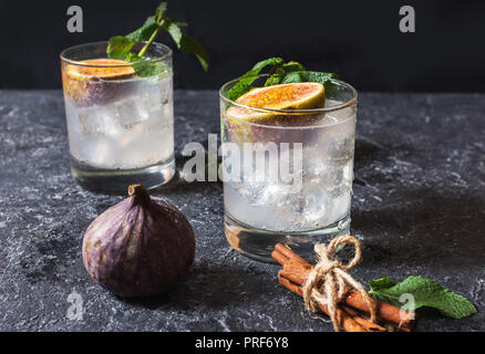 Pink fig alcoholic cocktail with cinnamon and mint on dark stone table. Stock Photo