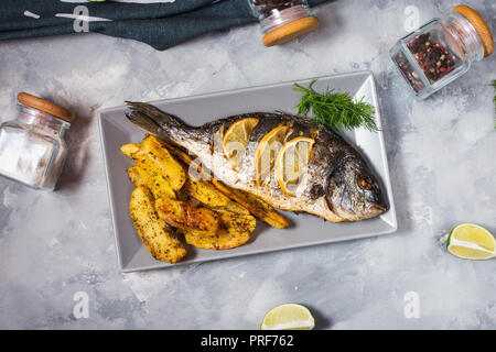Grilled fish on stone plate with lemon Stock Photo