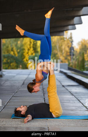 Young man and girl practicing acro yoga in city on the street Stock Photo