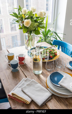 Cut roses and salad on scaffold board table in London home Stock Photo