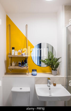 Circular mirror with diagonal paintwork in bathroom with rope shelf Stock Photo