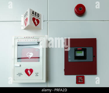 General view of a life saving defibrillator. Portable automated external defibrillator (AED) and fire alarm system mounted on the wall Stock Photo