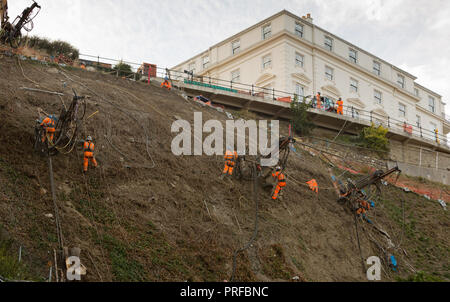 Construction engineers working in harnesses supported by cables working on cliff face at Scarborough. unsharpened Stock Photo