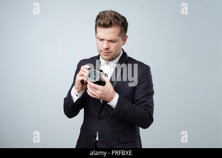I do not know how to use this new photocamera. Handsome young man trying to find out what setting is good Stock Photo