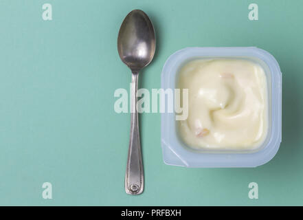Yogurt plastic cup with apricot yoghurt on green background with silver spoon - Top view photo Stock Photo