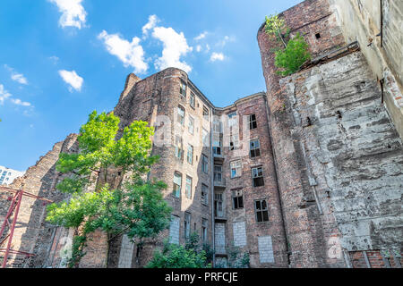 Facade of ruined old vintage red brick house with broken windows (location: Kamienico, part of former Jewish ghetto, Walicow street, Warsaw city, Pola Stock Photo