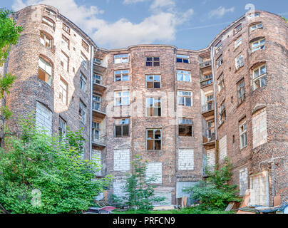 Facade of ruined old vintage red brick house with broken windows (location: Kamienico, part of former Jewish ghetto, Walicow street, Warsaw city, Pola Stock Photo