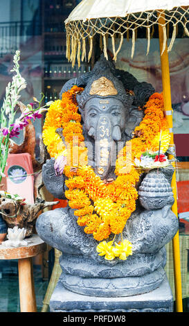 Big statue of Ganesha with yellow flowers necklace and umbrella Stock Photo