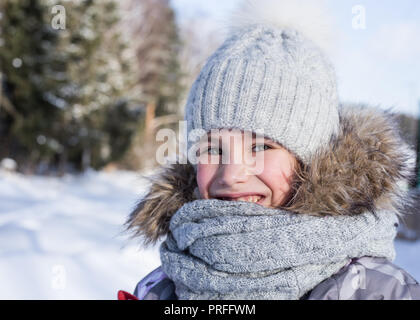 Winter portrait of happy little girl wearing knitted hat and scarf. Stock Photo