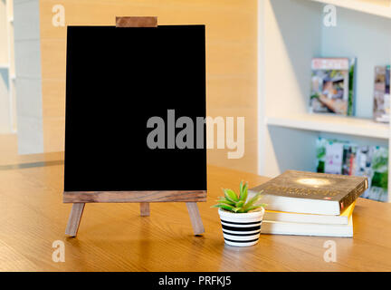Blank blackboard on wooden table,Template mock up for adding your design and leave space beside frame for adding more text. Stock Photo
