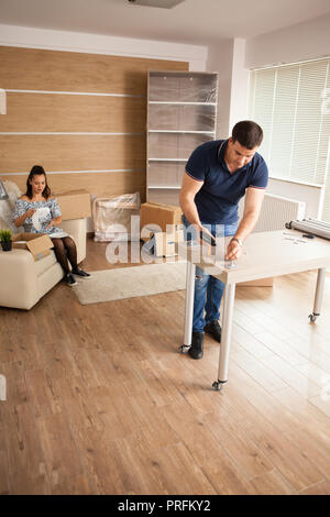 Man is working with furniture assembly using electric screwdriver in new house.Man using tools. Stock Photo