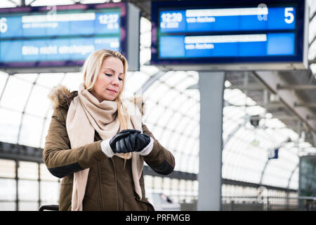 Woman looking at wristwatch in train station as her train has a delay Stock Photo