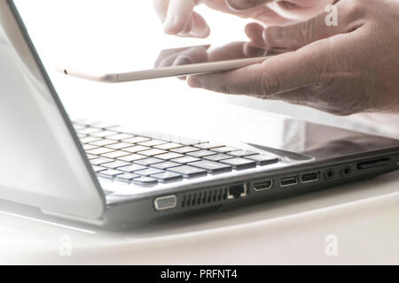 Man using an online banking web app holding a smartphone and a laptop computer. Empty copy space for Editor's text. Stock Photo