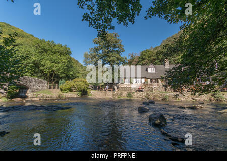 Fingle Bridge Inn next to the river Teign in Dartmoor with people outside eating and drinking Stock Photo