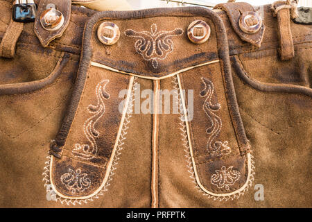 Closeup of flap (drop front) of  traditional bavarian and austrian lederhosen (leather pants). Lether relief and embroidered ornament. Decor elements. Stock Photo