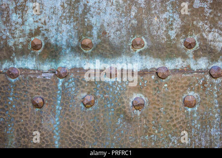 Texture of old weathered metal door with rivets. Vintage washed out rusty metal. Stock Photo