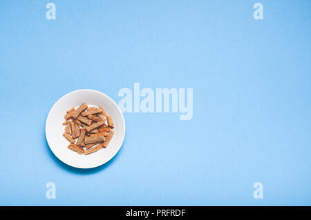 Brown roasted dry bread sticks croutons on white plate with copy space isolated on blue background Stock Photo