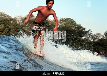 Surfer hanging ten while longboard surfing a wave in Batu Karas, Java, Indonesia Stock Photo