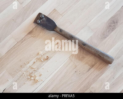 Hand scraper and wood shavings on an oak parquet floor in process of restoring. Stock Photo