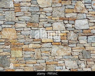 Stone granite wall made of stacked pieces stones. Full frame image as background.