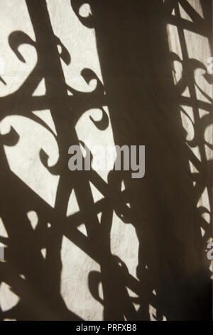 PATTERNS OF A GRILL FALLING AS SHADOWS ON A WALL Stock Photo