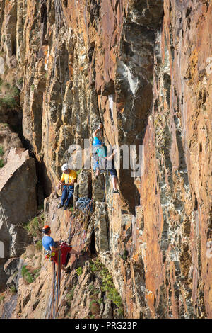 Portrait capture, three men enjoying challenge of extreme sport activity: abseiling and rock climbing on rockface at South Stack Cliffs, Anglesey, UK. Stock Photo
