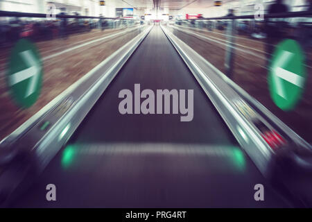 Perspective wide angle view of modern light blue illuminated and spacious high-speed moving commercial escalator with fast blurred trail of handrail i Stock Photo
