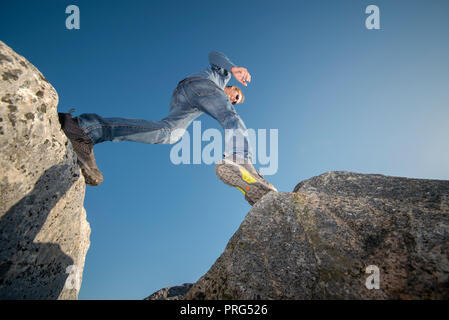 man stepping over boulders wearing walking shoes. Stock Photo