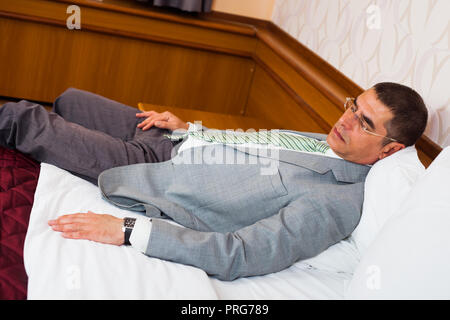 Tired businessman is sleeping on bed Stock Photo