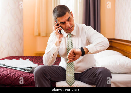 Businessman talking on phone and checking the time Stock Photo