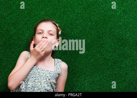Little girl is lying on artificial grass. She is tired and needs to sleep. Stock Photo