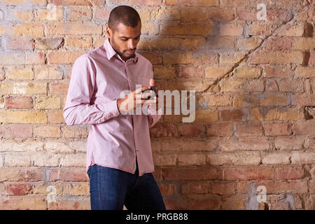A serious handsome young man holding a mug in a pink shirt. Stock Photo