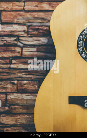 Acoustic guitar stands on a brick wall background. Stock Photo