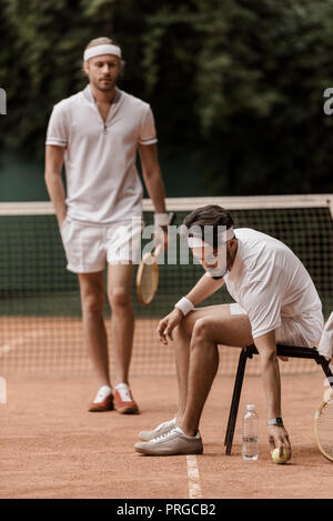 retro styled tennis player putting ball on ground at tennis court Stock Photo