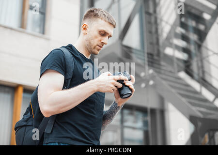 Attractive man next to staircase and checking photos in camera. Stock Photo