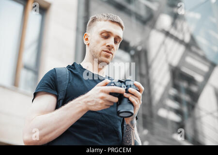 Attractive man next to staircase and checking photos in camera. Stock Photo