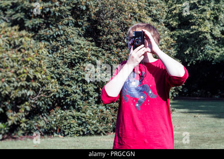 Teenage girl taking a photograph using an old 35mm plastic film camera Stock Photo