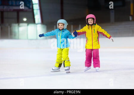 Children skating on indoor ice rink. Kids and family healthy winter sport. Boy and girl with ice skates. Active after school sports training for young Stock Photo