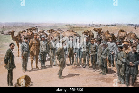 A hand tinted photograph from the First World War showing troops in a desert setting, standing alongside some Arab men with camels in the background Stock Photo