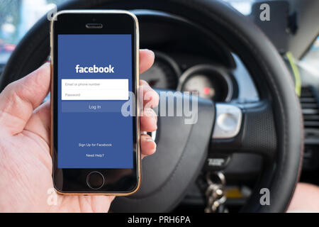 Facebook App on iPhone using social network when drive a car on road driving.23 September 2018,Bangkok Thailand. Stock Photo