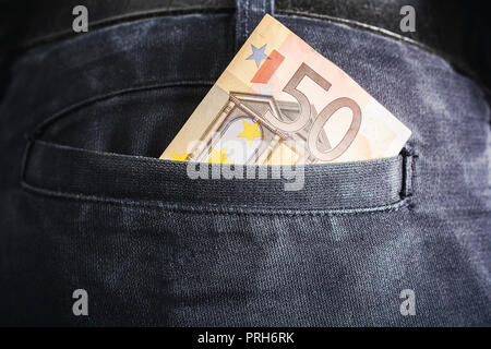 Half Of A 50 Euro Bill Showing Out Of The Back Pocket Of A Black Jeans Trouser - Rich Man Concept Stock Photo