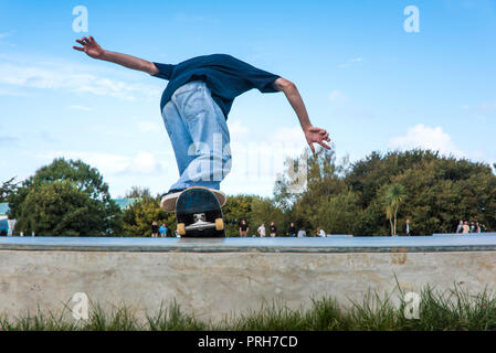 A skateboarder launching from a deck at Concrete Waves Skateboard Park in Newquay in Cornwall. Stock Photo