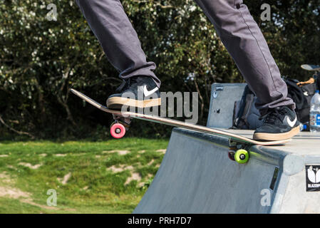 A skateboarder wearing Nike trainers pushing off from a deck at Concrete Waves in Newquay in Cornwall. Stock Photo