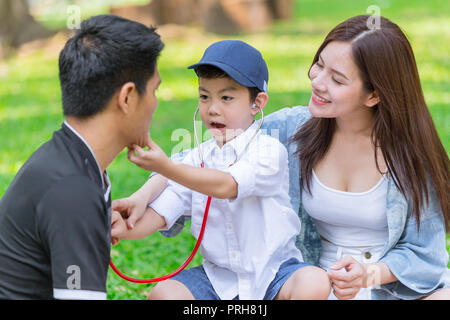 Asian teen family teaching son homework while picnic at outdoor park Stock Photo