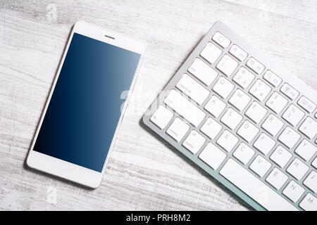 Mobile With Reflection Lying Next To A White Keyboard On A Table Stock Photo