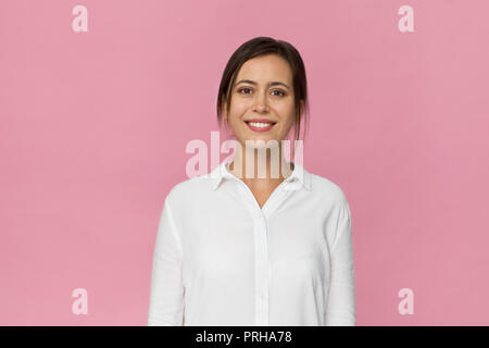 Smiling positive female close up with attractive look posing against pink background Stock Photo
