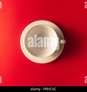 Flat lay view of the one white empty white coffee or tea cup on red color background, closeup, copy space. Stock Photo
