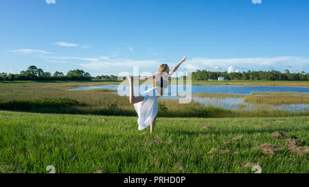 Young blonde woman doing a yoga pose standing on one leg and stretching  near a white wall. Utthita Hasta Padangusthasana Stock Photo - Alamy