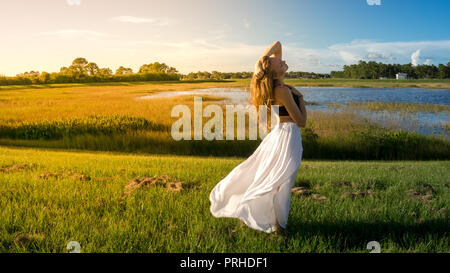 Young slim woman with blonde hair sitting on the yoga mat in split and  training her stretching - using auxiliary stand under the feet Stock Photo  - Alamy